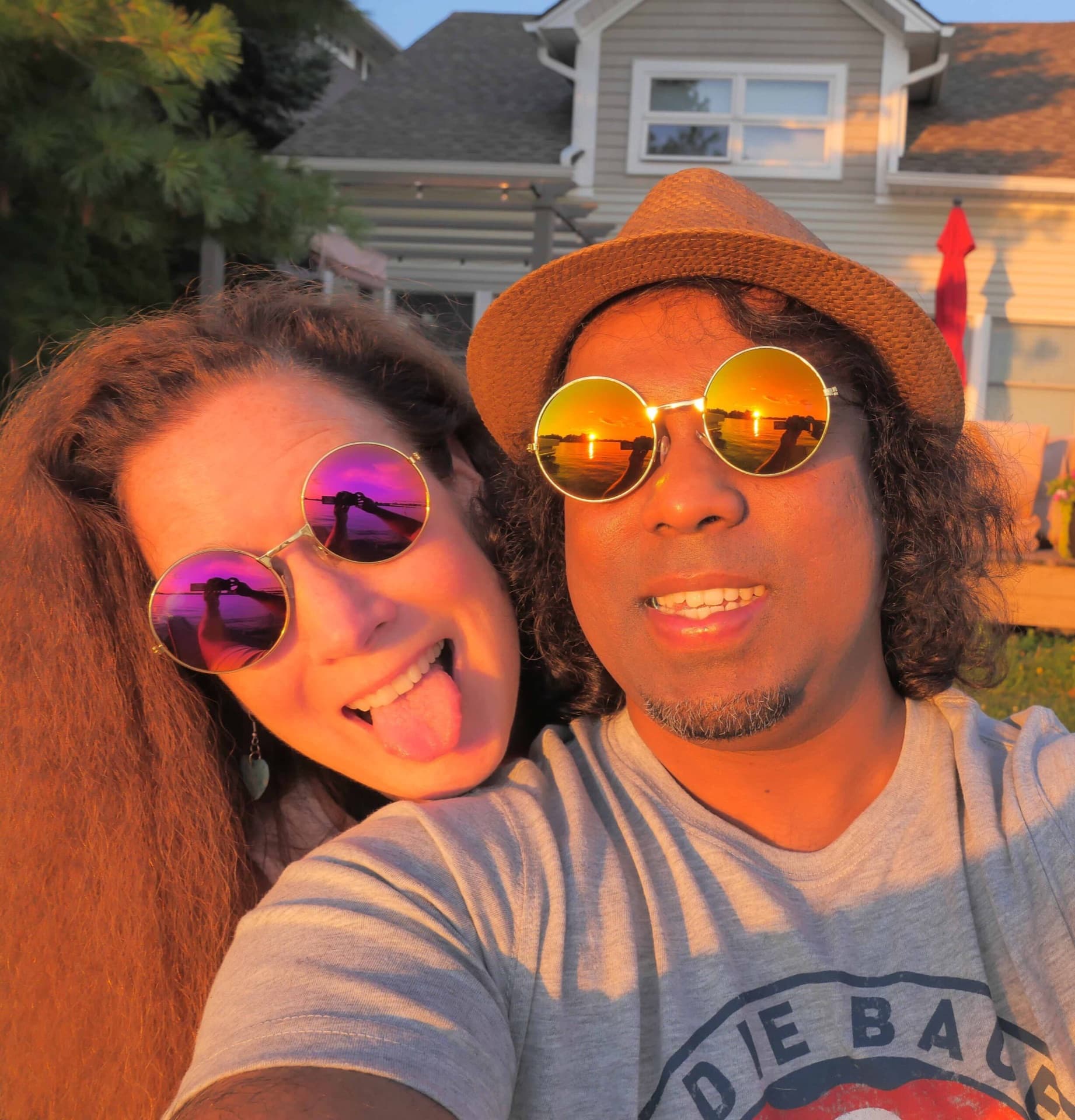 Couple in round mirrored sunglasses grinning into a golden-hour selfie